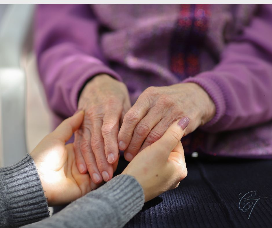 A set of hands gently grasping a set of older hands
