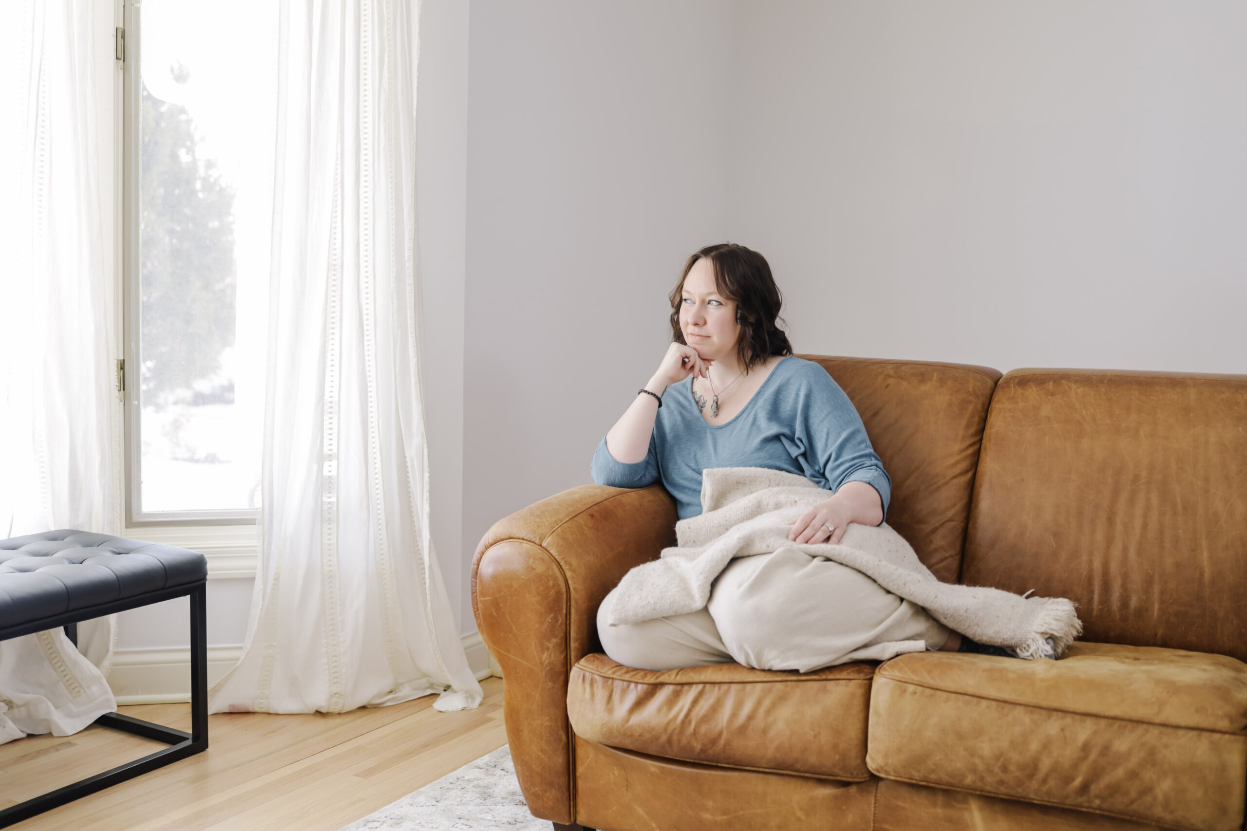 Woman sitting on couch looking off into distance